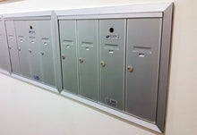 Load image into Gallery viewer, A silver, multi door recessed mounted mailbox with locks on the front. 
